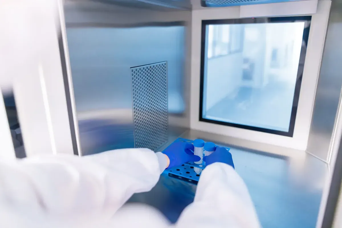 Hands in cleanroom gloves working inside a sterile cabinet